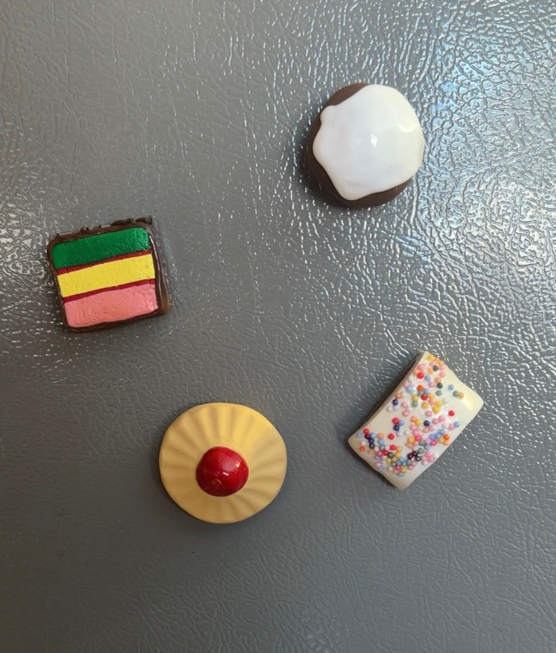 Four colorful miniature desserts on a gray surface
